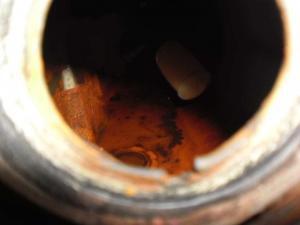 The inside of a fuel tank showing heavy contamination with rust and sludge